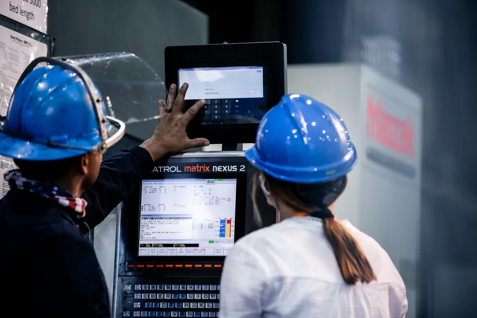 Two machinists reviewing production data together on the shop floor